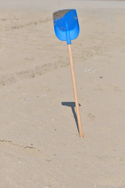Синя лопата з пластику з дерев'яним хвостом для дітей в піску на — стокове фото