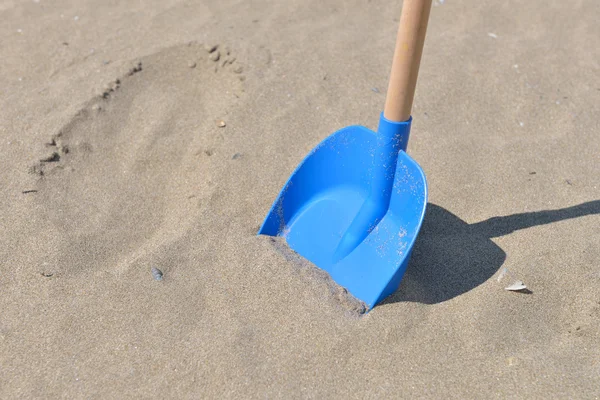 Pá azul de plástico com cauda de madeira para crianças na areia em um — Fotografia de Stock
