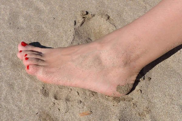Pies de mujer con pedicura roja caminando sobre la arena caliente de la playa — Foto de Stock