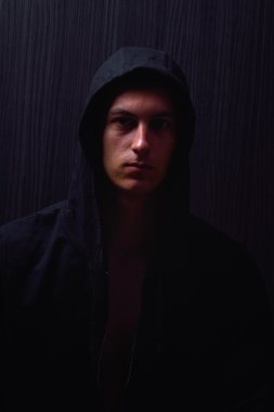 Ciddi ifade ve siyah kapüşonlu genç çocuk portresi