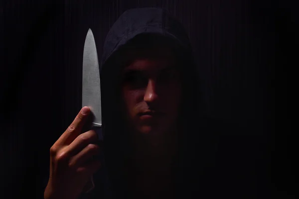 Closeup πορτρέτο ενός νεαρού άνδρα σε ένα φούτερ με κουκούλα, κρατώντας ένα μαχαίρι στο Royalty Free Εικόνες Αρχείου