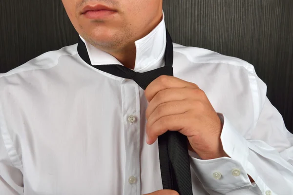 Detail van een man in een wit overhemd tot vaststelling van zijn zwarte stropdas in een studi — Stockfoto