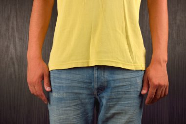Young man wearing yellow blank t-shirt, on dark background. Pict