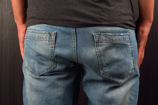 Achterkant van jonge man met grijs leeg t-shirt, permanent in een stud — Stockfoto