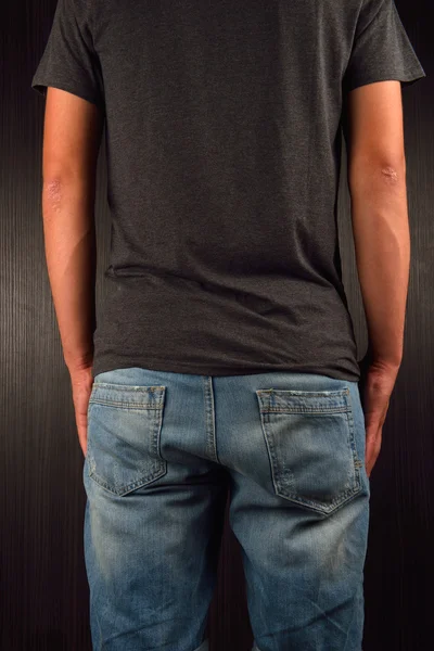 Baksidan av ung man klädd i grå blank t-shirt, stående i en stud — Stockfoto