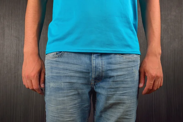 Young man wearing blue blank t-shirt, on dark background. Pictur — 图库照片