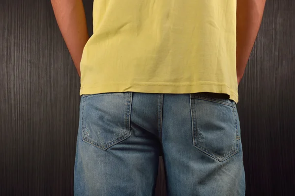 背着穿着黄色空白T恤的年轻人，站在一个 — 图库照片