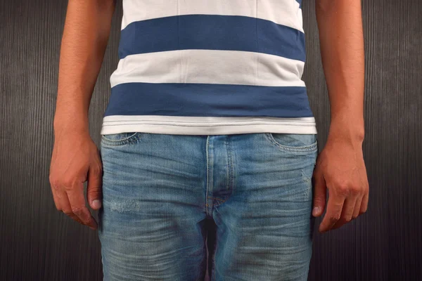 Young man wearing white t-shirt with blue stripes, on dark backg — ストック写真