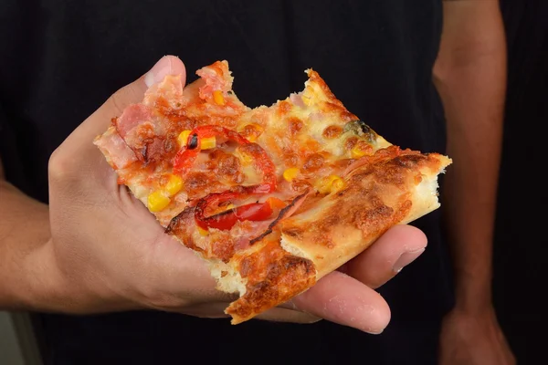 Hand of a man holding a tasty slide of pizza isolate on dark bac — Stock Photo, Image