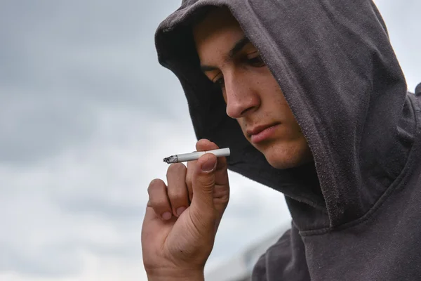 Genç adam sigara baktı ve sm olup olmadığını için kararsız olduğunu — Stok fotoğraf