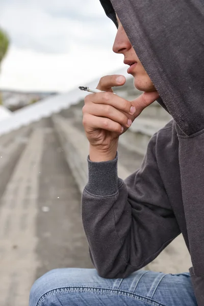 Young man in depression smoking a cigarette on a stadion. Concep — Stock Photo, Image