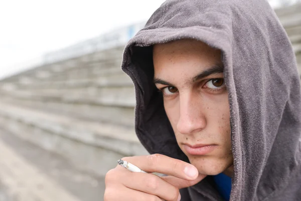 Jovem em depressão fumando um cigarro em um estádio e loo — Fotografia de Stock