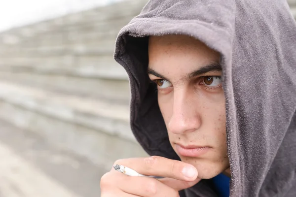 Un joven deprimido fumando un cigarrillo en un estadión. Concep — Foto de Stock