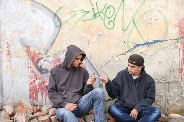 Dos vándalos callejeros o raperos de pie contra un dolor de graffiti — Foto de Stock