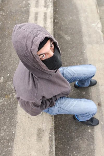 Unrecognizable young man wearing black balaclava sitting on old — Stock Photo, Image