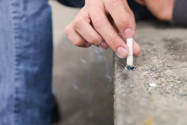 Rukou mladého muže uhasit cigaretu na schody — Stock fotografie