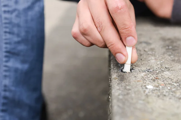 Hand of a young man extinguish cigarette on a stair — Stock Photo, Image