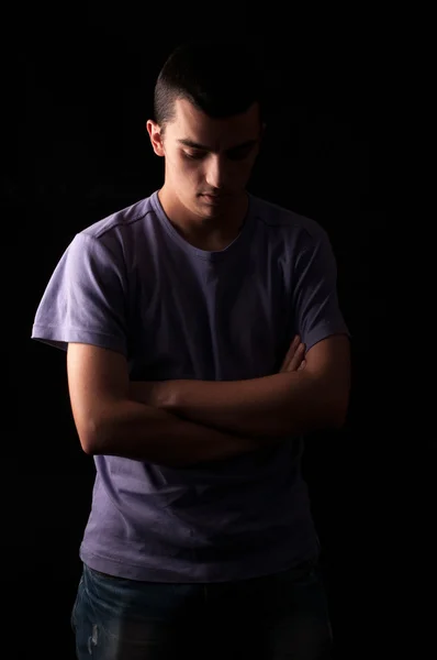 Ernster junger Mann mit verschränkten Armen auf schwarzem Hintergrund — Stockfoto