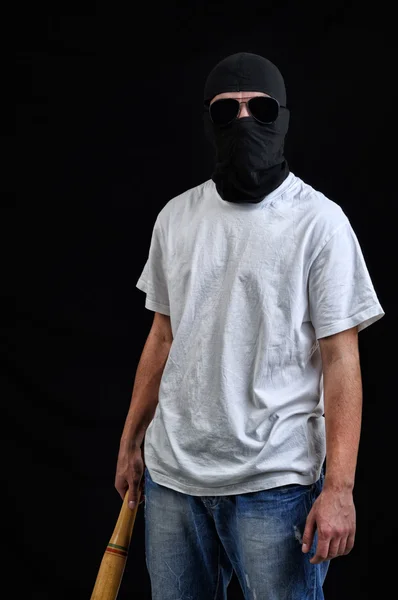 Человек в маске готовится к атаке битой — стоковое фото