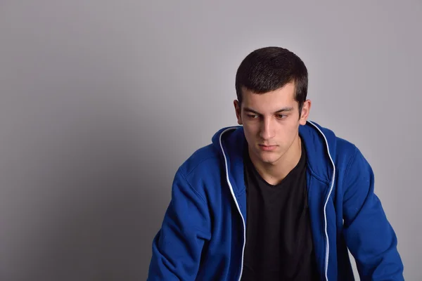 Denker aantrekkelijke jonge man in een blauwe hoodie — Stockfoto