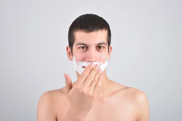 Closeup de un hombre joven que se preparaba para afeitarse, pone la espuma en su c — Foto de Stock