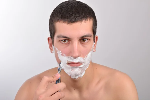 Bello giovane uomo con un sacco di crema da barba sul viso prepar — Foto Stock