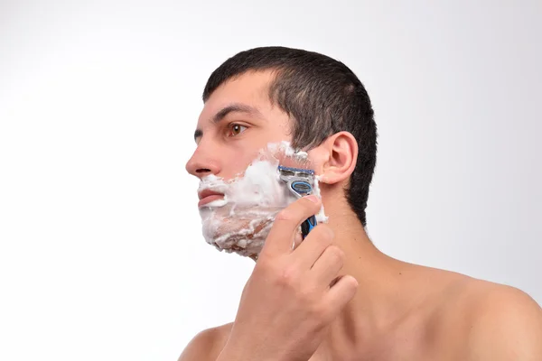 Bello giovane uomo con un sacco di crema da barba sul viso prepar — Foto Stock