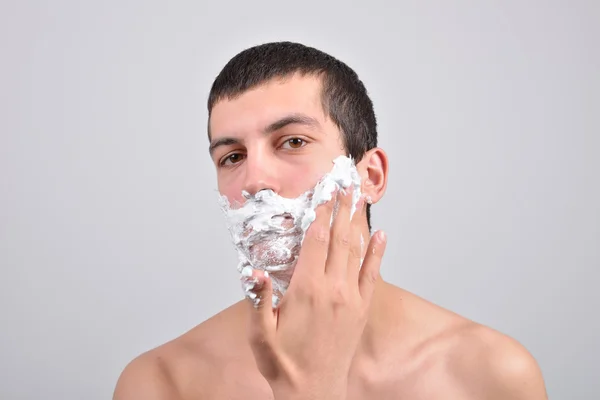 Fechar-se de um jovem se preparando para barbear, ele coloca espuma em seu c — Fotografia de Stock