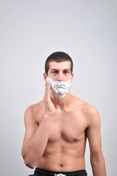 Closeup de un hombre joven que se preparaba para afeitarse, pone la espuma en su c — Foto de Stock