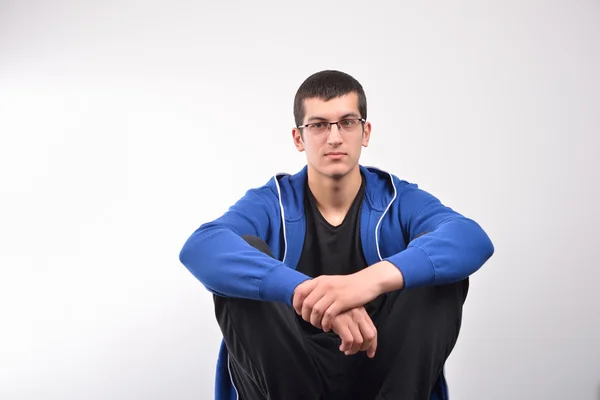 Vermummter junger Mann sitzt gegen Wand — Stockfoto