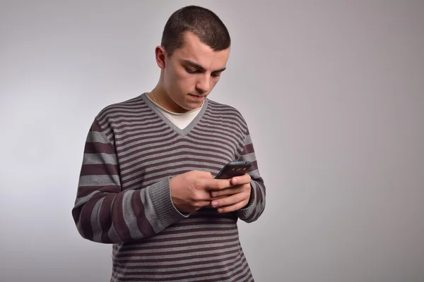 Giovane uomo guardando il suo smartphone mentre messaggistica di testo — Foto Stock