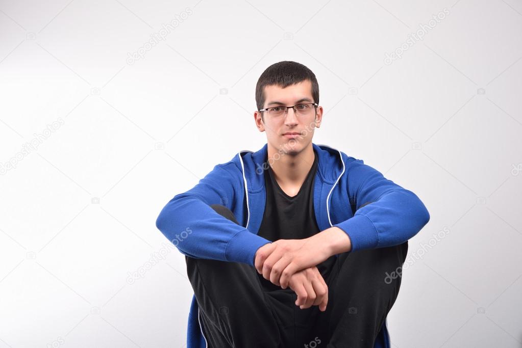 Hooded young man sitting against wall