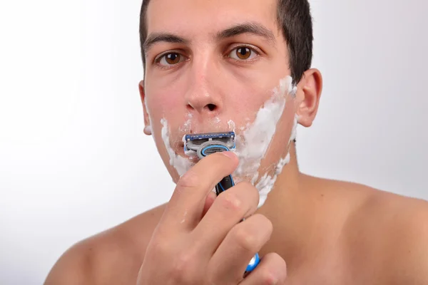 Hombre joven guapo con un montón de crema de afeitar en la cara es sha — Foto de Stock