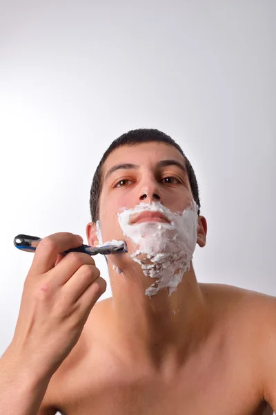 Handsome young man with lots of shaving cream on his face is sha — Stock Photo, Image