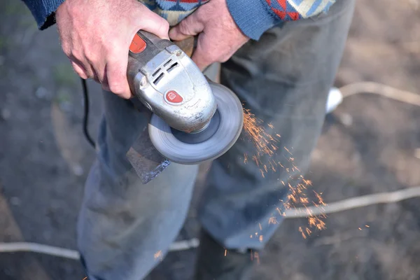 Close-up van een man een bijl met behulp van elektrische grinder verscherpen. Sparks w — Stockfoto