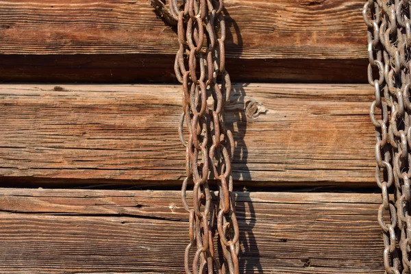 Zardzewiały łańcuch wisi na stare drewniane ściany — Zdjęcie stockowe