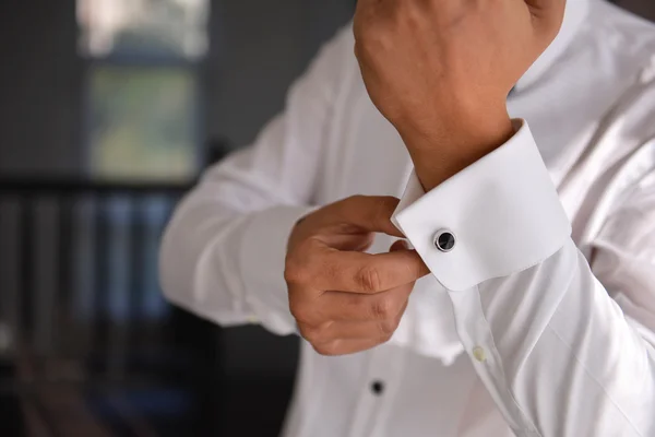 Close up de um homem de mão como veste camisa branca e abotoaduras — Fotografia de Stock
