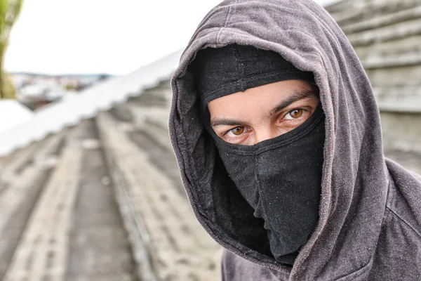 Unrecognizable young man wearing black balaclava sitting on old — Stock Photo, Image