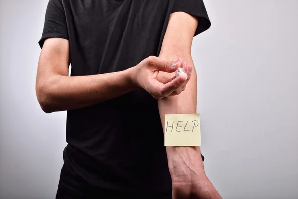 Hand met heroïne spuit met post-it die zegt help — Stockfoto