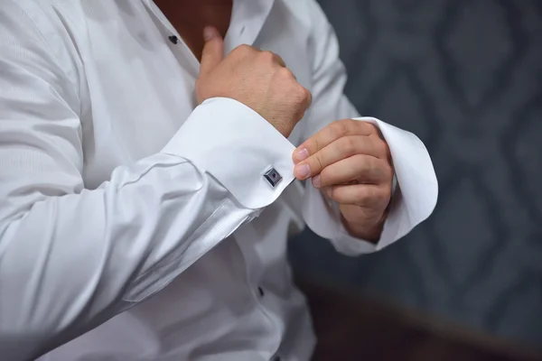 Close up de um homem de mão como veste camisa branca e abotoaduras — Fotografia de Stock
