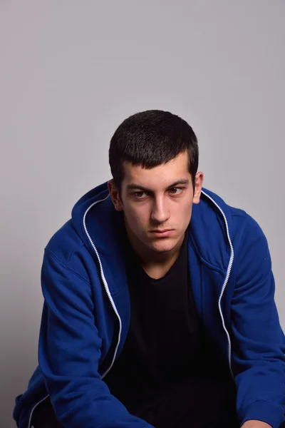 Adolescente triste con felpa blu in piedi contro un muro sporco — Foto Stock