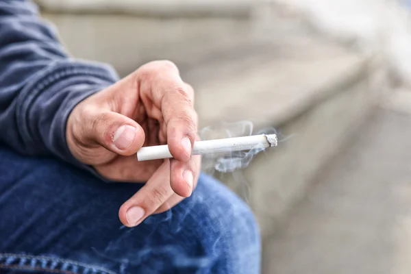 Jovem mão masculina segurando um cigarro — Fotografia de Stock