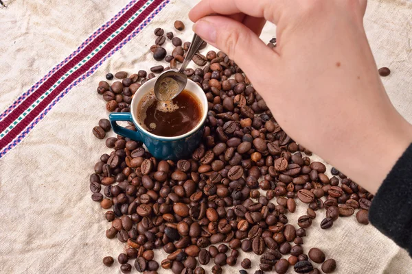 Granos de café tostados con taza y cuchara sobre fondo de yute —  Fotos de Stock