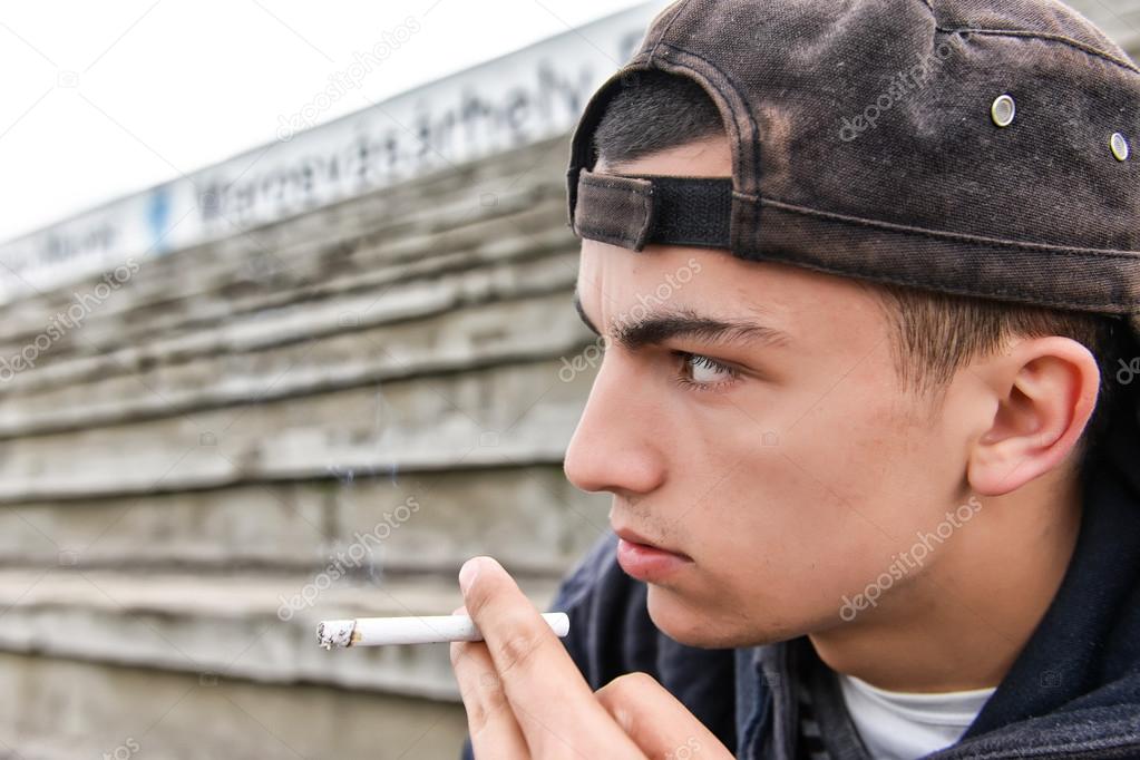 Teenage boy smoking cigarette outdoor. Concept of young people w