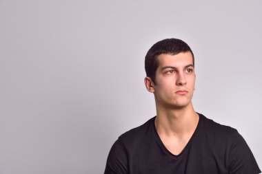 Portrait of a serious young man standing against grey background
