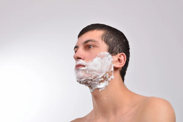 Closeup of a young man preparing to shave, he puts foam on his c — Stock Photo, Image
