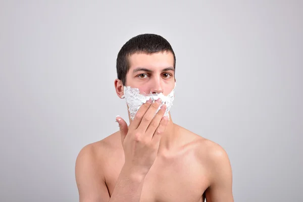 Closeup de un hombre joven que se preparaba para afeitarse, pone la espuma en su c — Foto de Stock