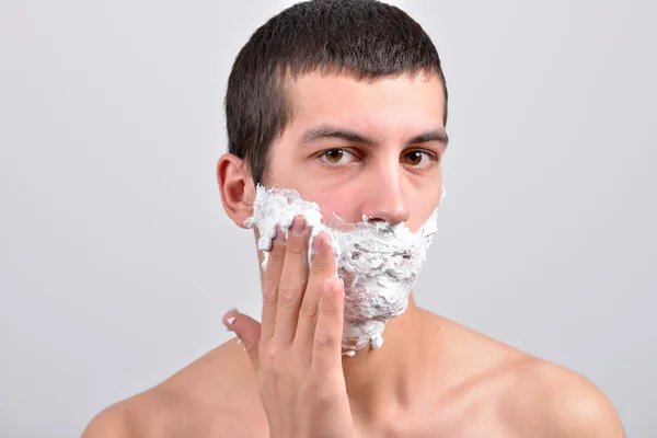 Closeup de un hombre joven que se preparaba para afeitarse, pone la espuma en su c — Foto de Stock