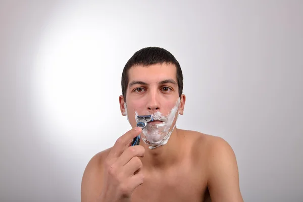 Atractivo joven con un montón de crema de afeitar en su veterinaria de cara —  Fotos de Stock
