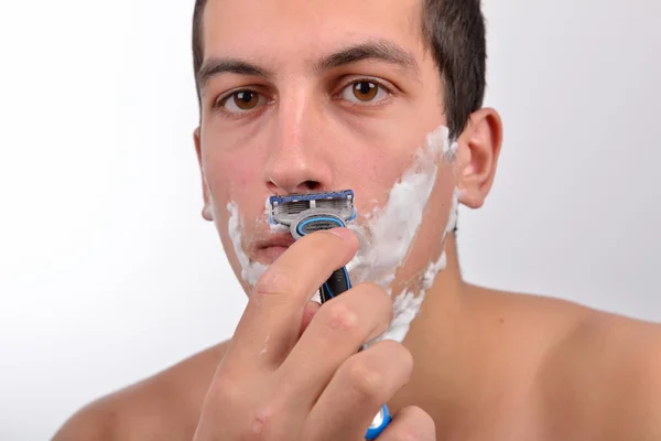 Bello giovane uomo con un sacco di crema da barba sul viso prepar — Foto Stock